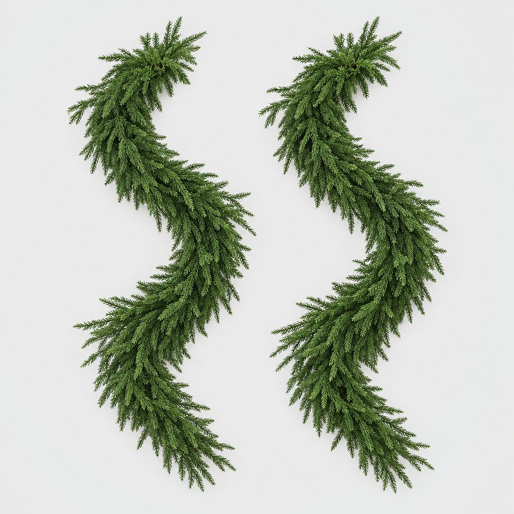 Two full green Norfolk pine garlands laid in S-curves on a plain light gray background