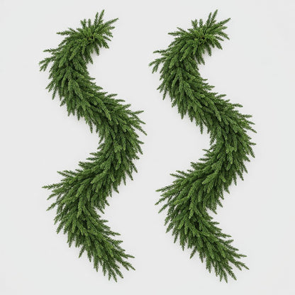 Two full green Norfolk pine garlands laid in S-curves on a plain light gray background