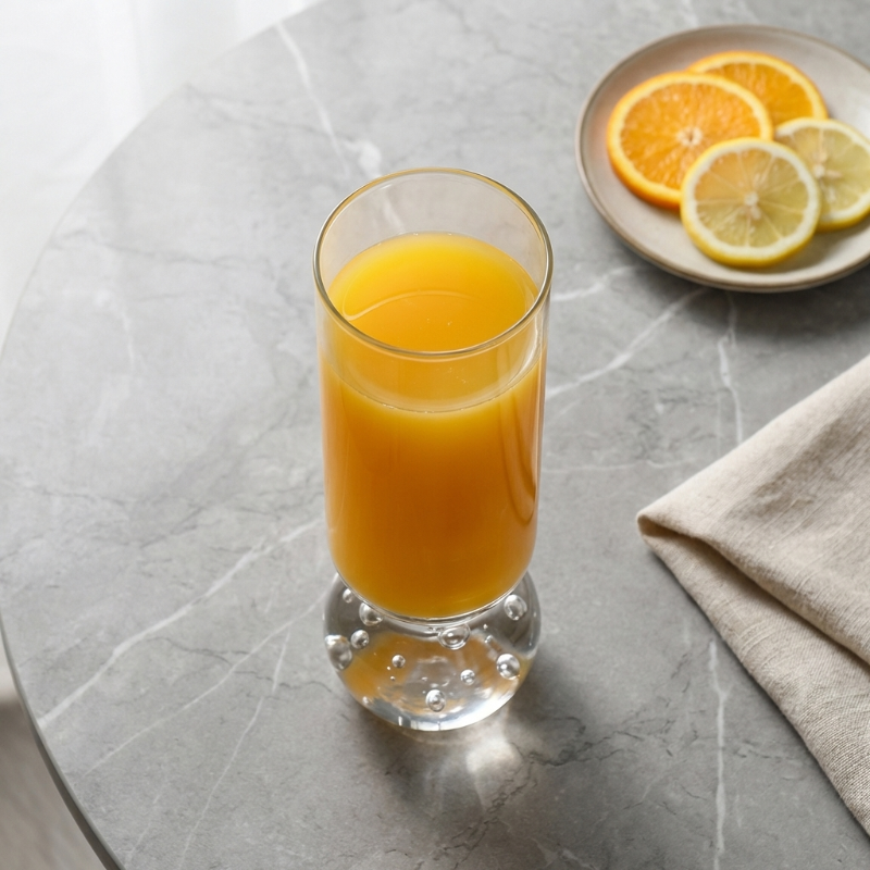 Orb base glasses with orange juice on marble table