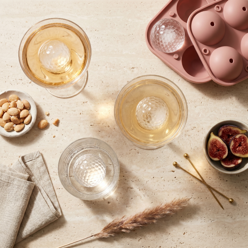 Golf ball ice mold tray with drinks and snacks on table