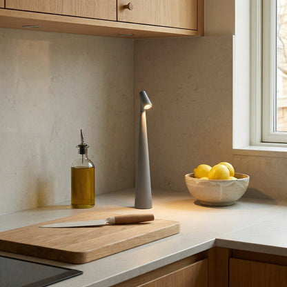 Modern kitchen counter with a cutting board, knife, bottle of oil, and bowl of lemons.