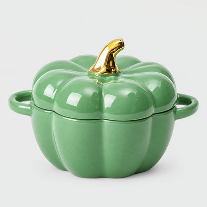 Single glossy sage green ceramic pumpkin bowl with ribbed lid, gold stem and two loop handles on a plain light backdrop