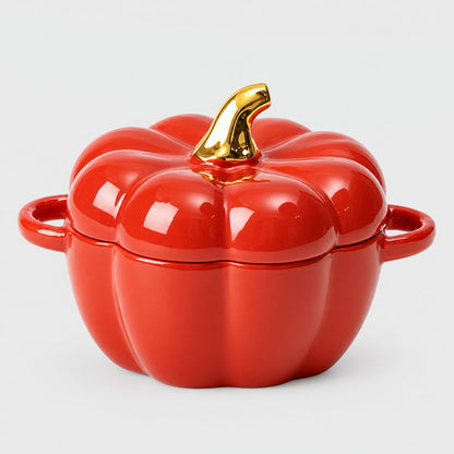 Single glossy red ceramic pumpkin bowl with ribbed lid, gold stem and two loop handles on a plain light backdrop