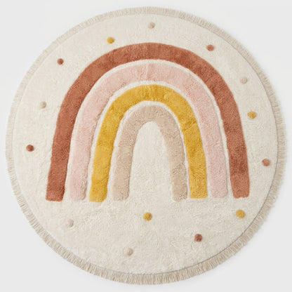 Rainbow Education Plush Nursery Play Mat in a round shape with a pastel terracotta, pink, mustard, and cream rainbow design and pom-pom accents