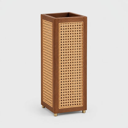 Tall square rattan cane umbrella stand with a dark wood frame and small brass feet on a light grey background
