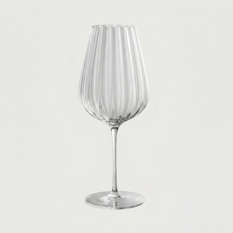 Clear glass wine glass with vertical stripes on a light gray background