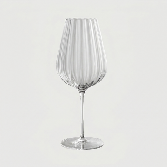 Clear glass wine glass with vertical stripes on a light gray background