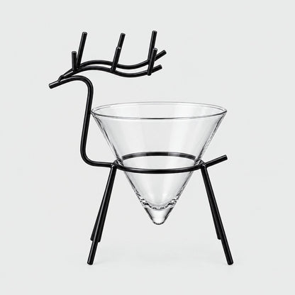 Black metal reindeer stand with antlers holding an empty clear cone cocktail glass on a light grey background