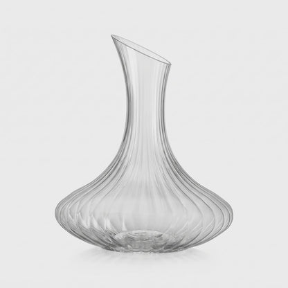 Empty ribbed glass wine decanter with a slanted neck on a plain light background