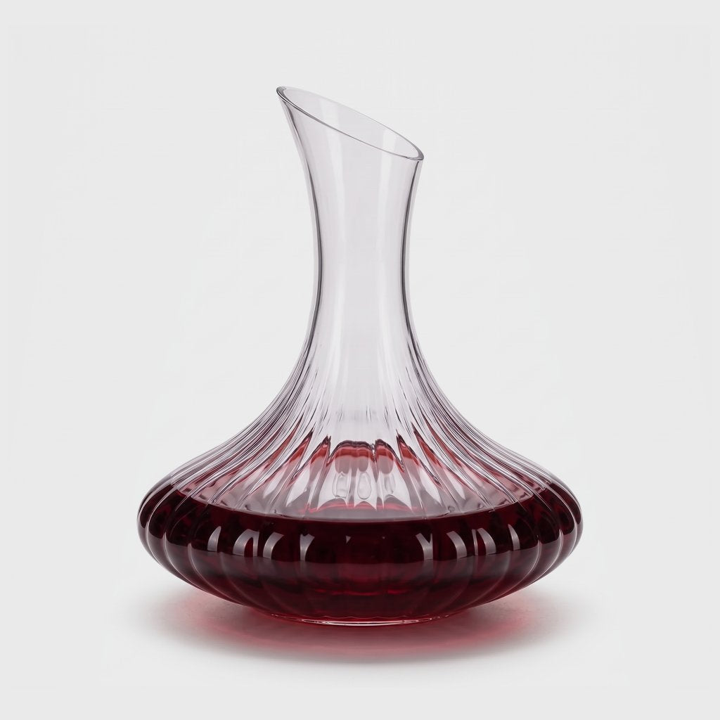 Ribbed glass wine decanter with red wine on a plain light background