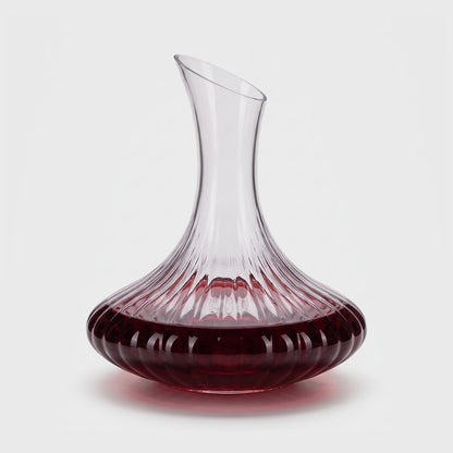 Ribbed glass wine decanter with red wine on a plain light background