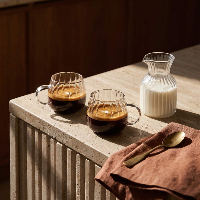 Ribbed glass mugs on bed tray with coffee and snacks