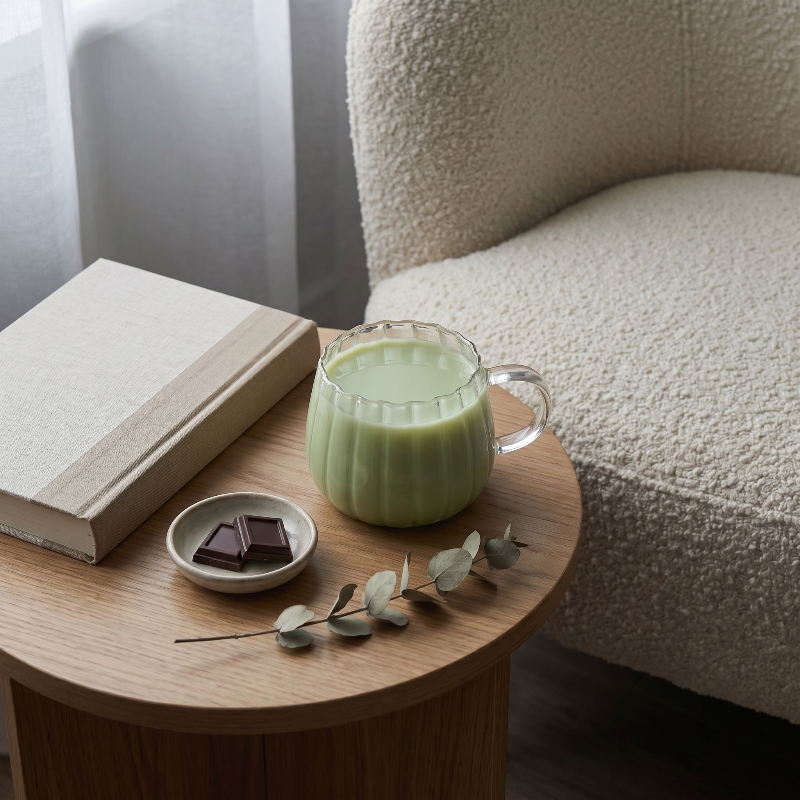 Ribbed glass mug with green drink on side table beside sofa