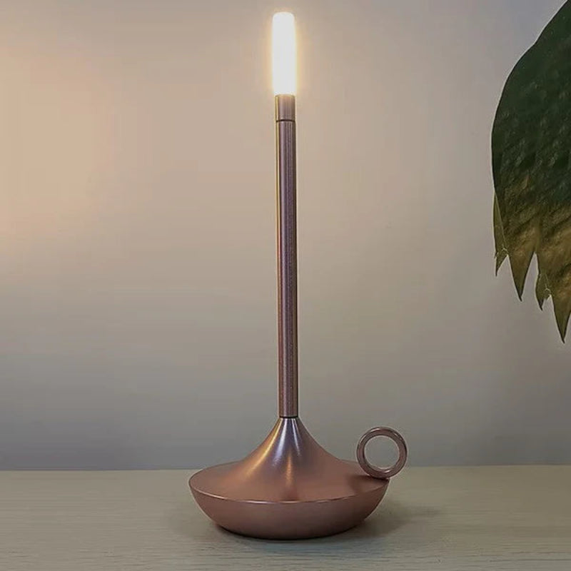 Rose gold portable, dimmable candle lamp styled on a shelf.