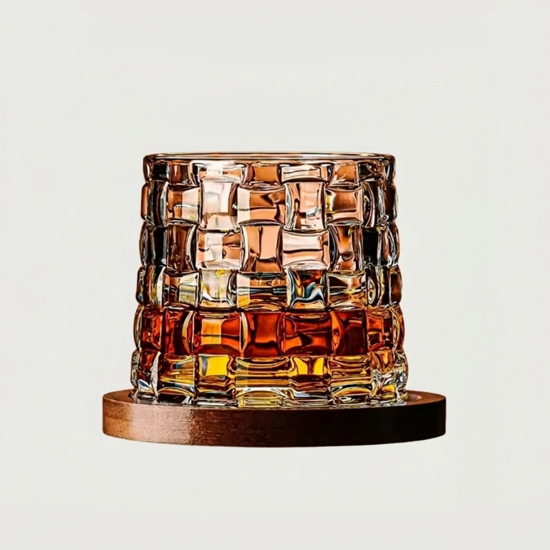 Square-cut rotating whiskey glass with amber whiskey on wood coaster