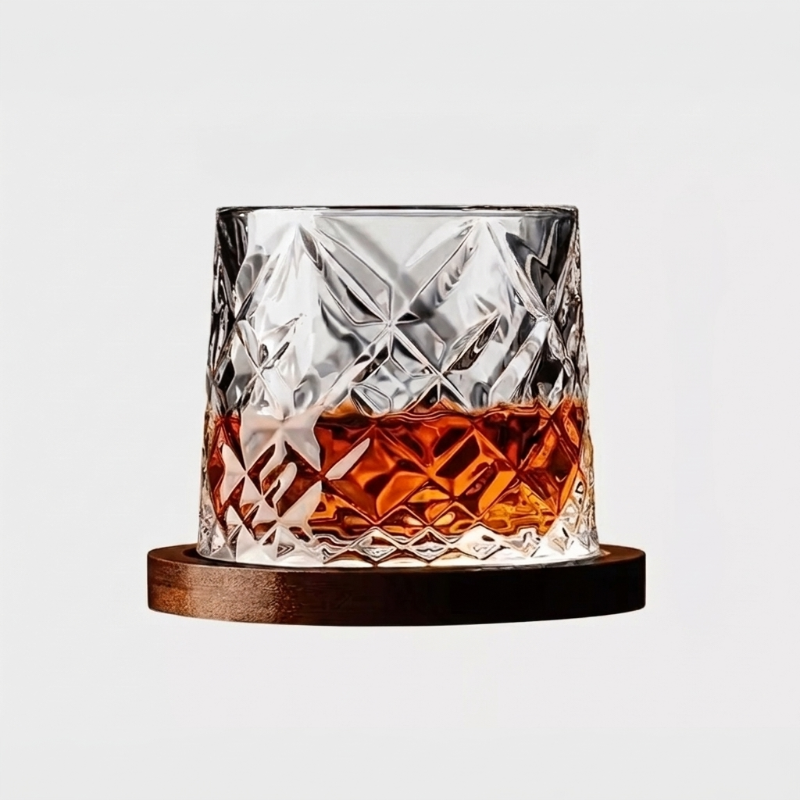 Faceted rotating whiskey glass with wood coaster on white background