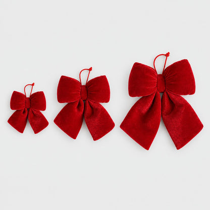 Small, medium and large red velvet bows side by side on a plain light background