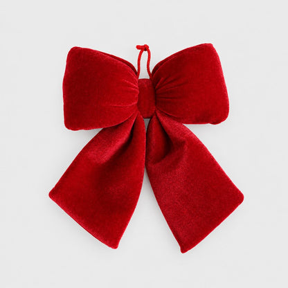 Medium red velvet bow with a red hanging loop on a plain light background
