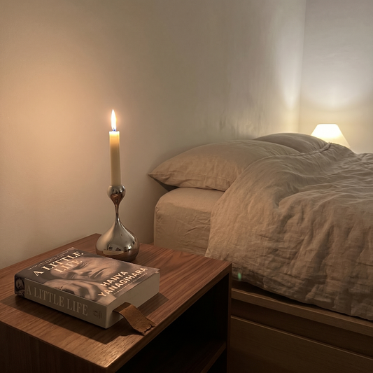 Sculpted chrome taper candle holder on bedside table in softly lit bedroom