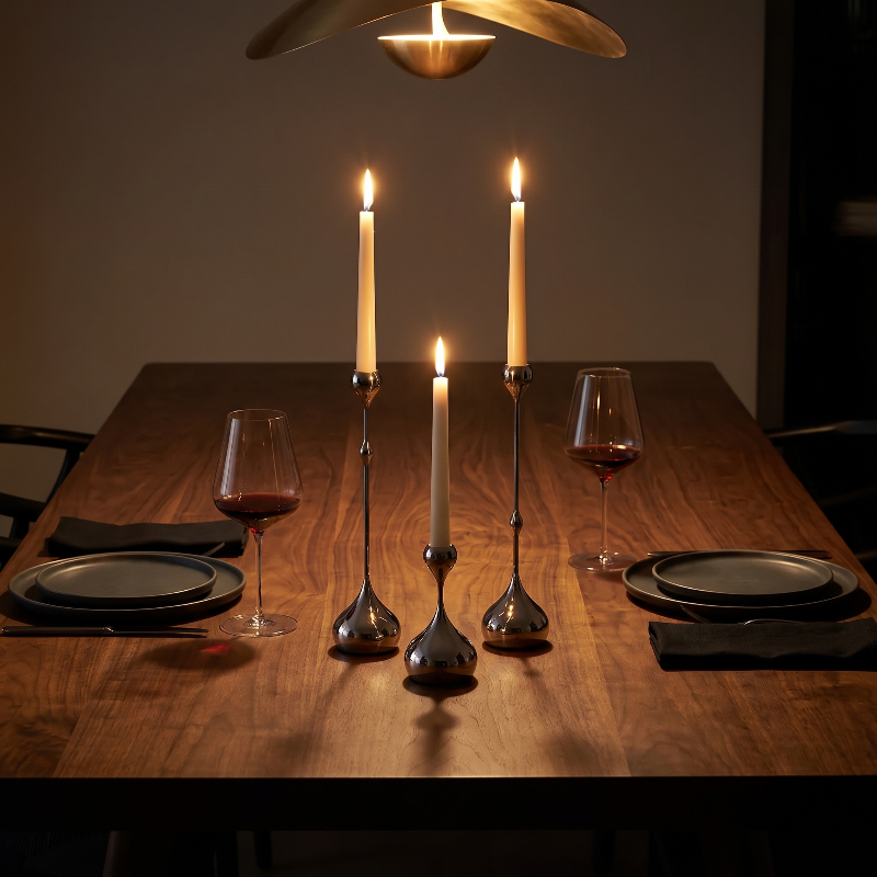 Dining table set with candles, wine glasses, and plates in a dimly lit room.