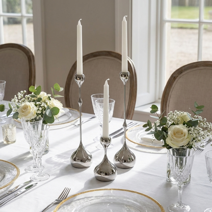 Elegant table setting with silver candle holders, white candles, and floral arrangements.