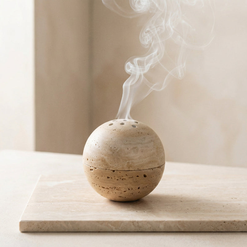 Spherical stone incense burner with smoke on a light wooden surface