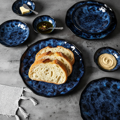Blue ceramic plates with bread and spreads on a gray surface