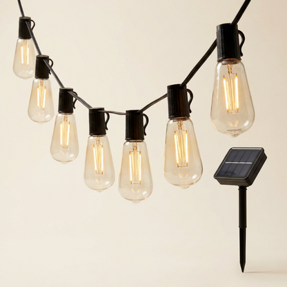String of illuminated light bulbs with a solar panel on a neutral background