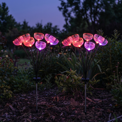 Two color-changing jellyfish-style fiber-optic solar garden light stakes glowing in a garden bed