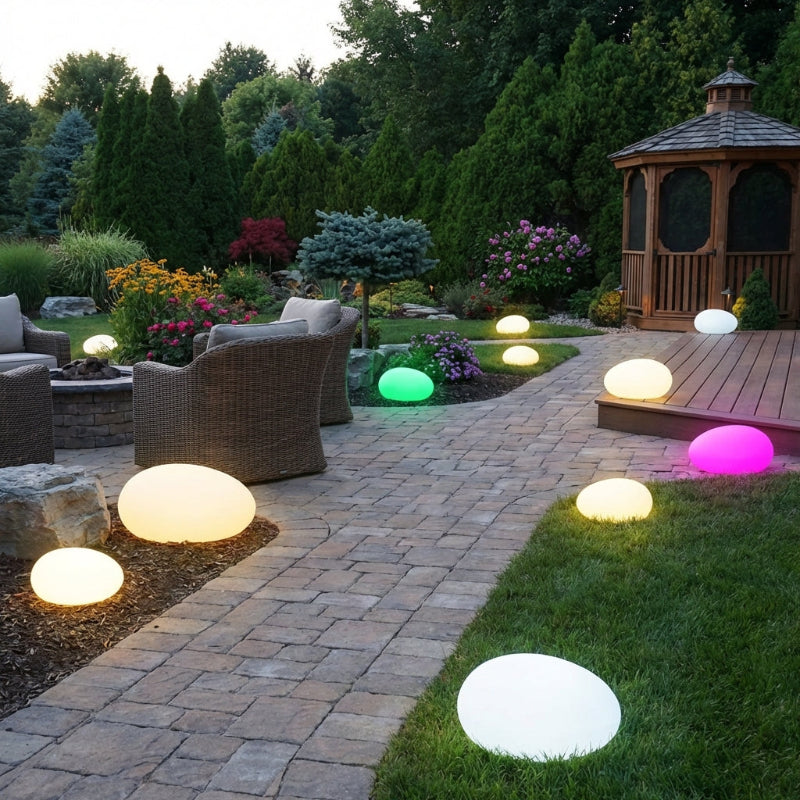 Outdoor patio with colorful LED lights on grass and stone pathway, surrounded by garden and gazebo.