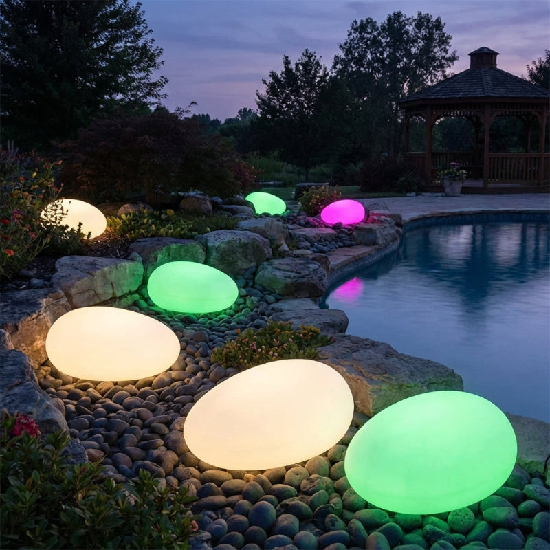 Glowing colorful lights on pebbles by a pool at night