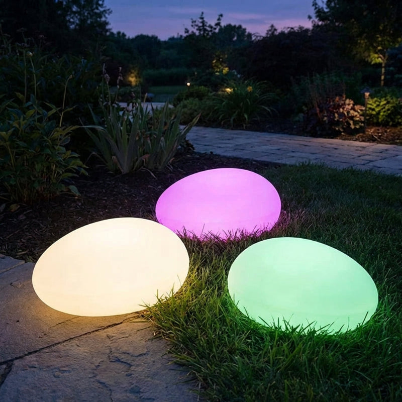 Three colorful LED lights on grass at night