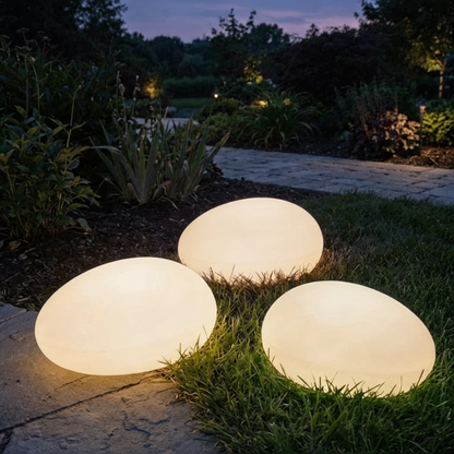 Three illuminated outdoor spherical lights on grass at night