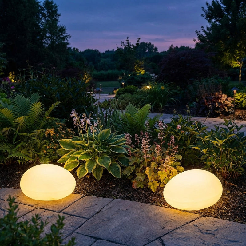 Two spherical garden lights illuminating a garden at night.