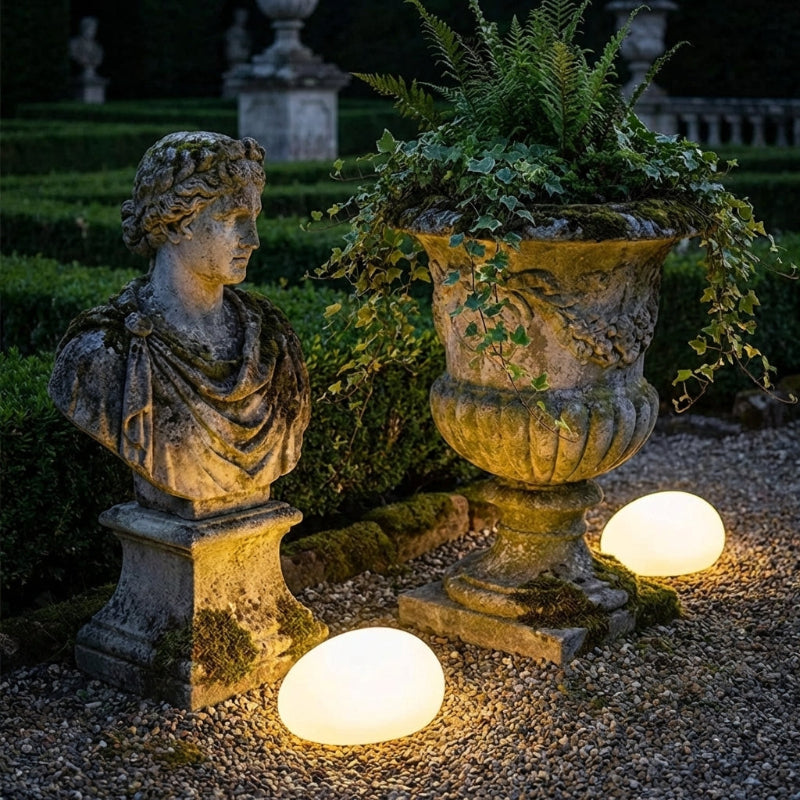 Stone bust and urn with illuminated lights in a garden setting