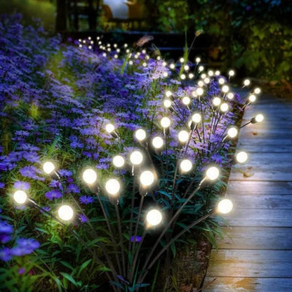 Solar swaying garden lights illuminating a pathway, mixed in between purple flowers.