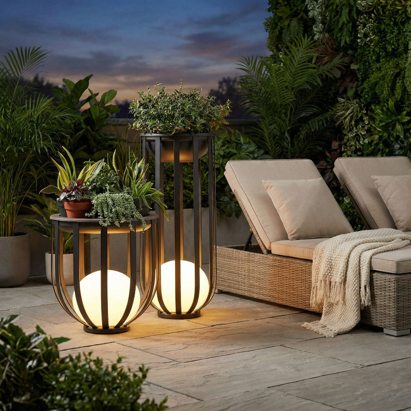 Outdoor setting with two illuminated lanterns on a patio, surrounded by plants and a couch.