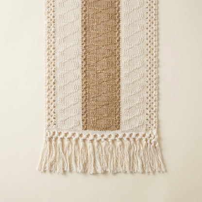 Textured woven wall hanging with striped pattern and tassels on a beige background