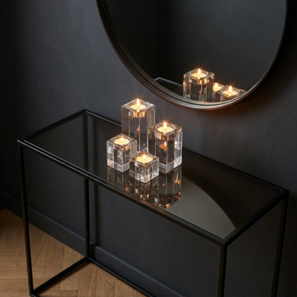 Square glass candle holders on black console table beneath round mirror