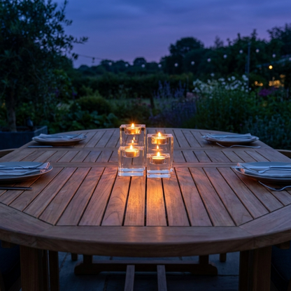 Square glass candle holders glowing on outdoor dining table at dusk