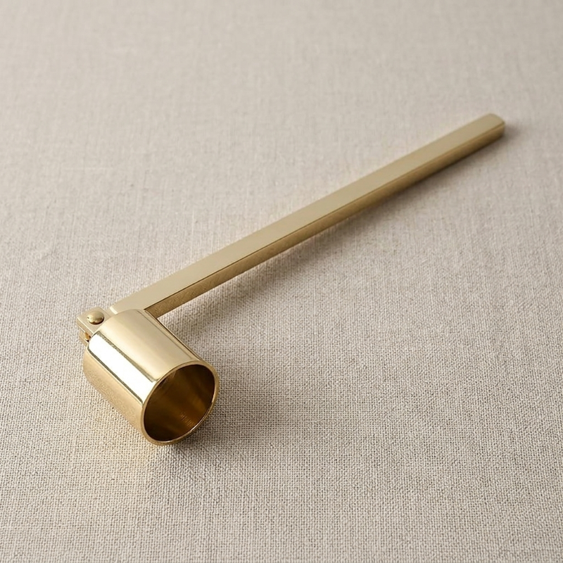 Gold stainless steel candle snuffer on white background