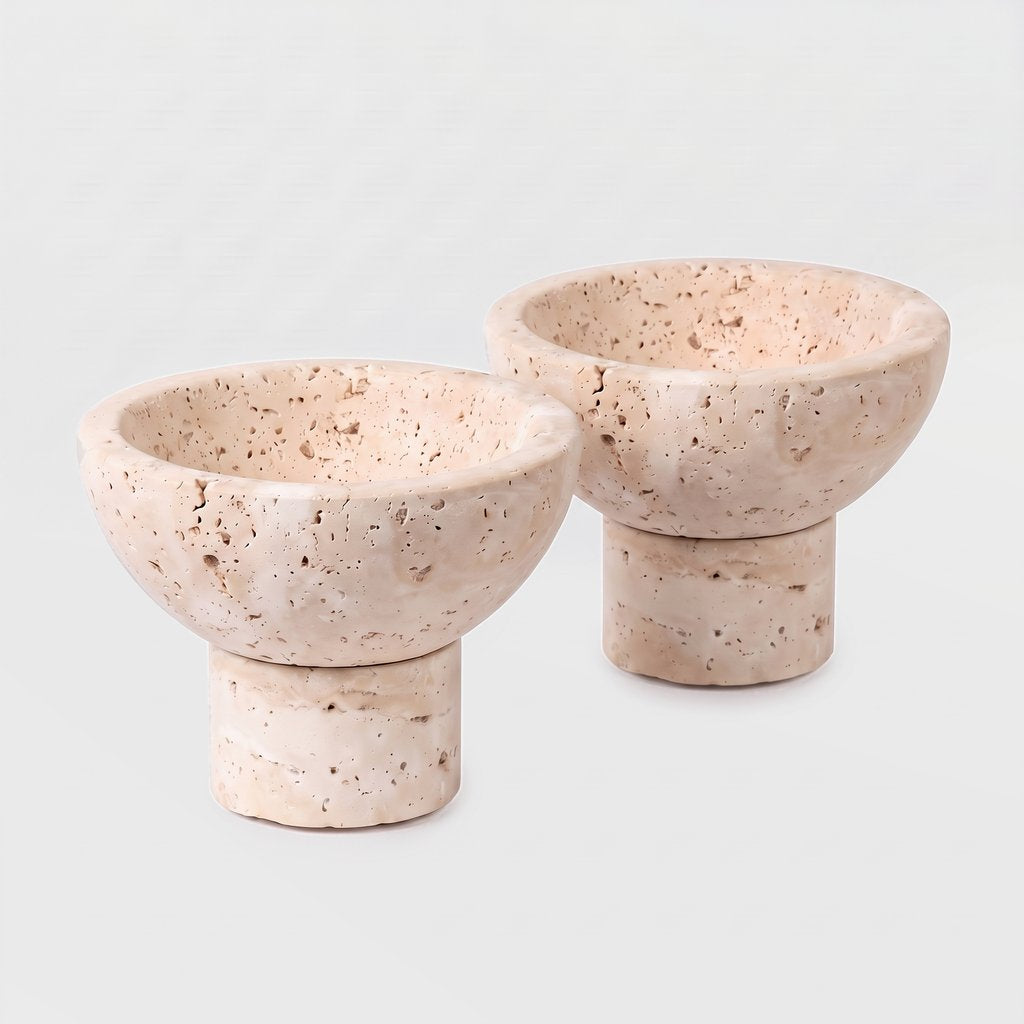 Two round pale stone pedestal bowls on a plain light background