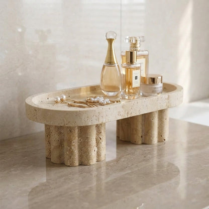 Decorative stone shelf with perfume bottles and jewelry on a marble floor.