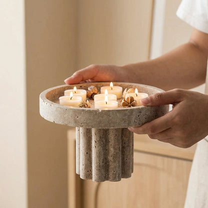 Person holding a concrete candle holder with lit candles and decorative elements.