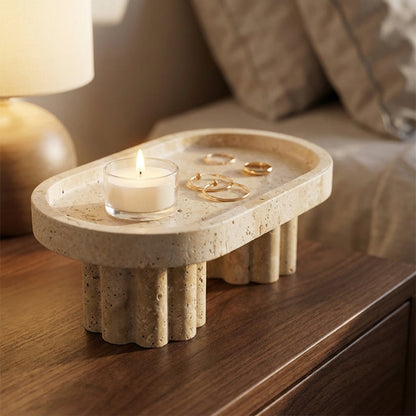 Decorative stone tray with a candle and rings on a wooden surface.
