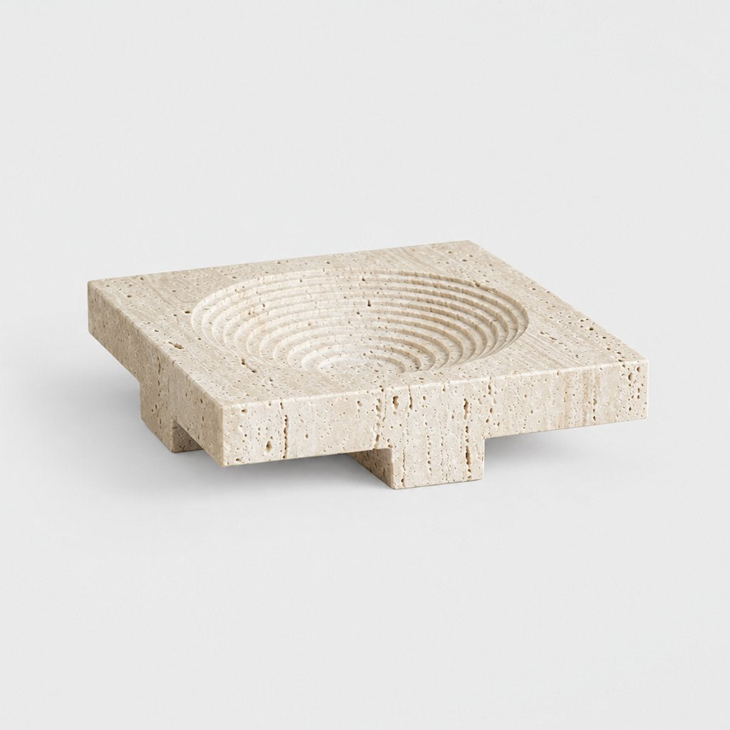 Square pale beige pedestal tray with a round ridged dish and block feet, on a plain light gray background
