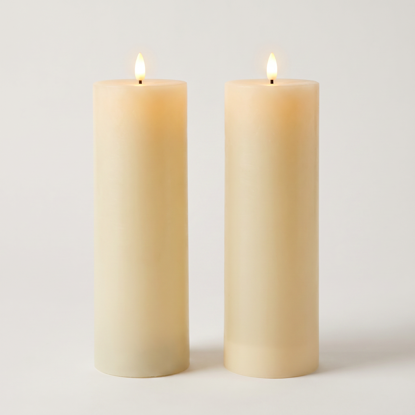 Set of two tall beige waterproof LED flameless pillar candles on an off-white background