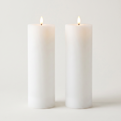 Set of two tall white waterproof LED flameless pillar candles on an off-white background