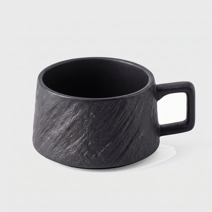 Black textured ceramic cup on a plain light background