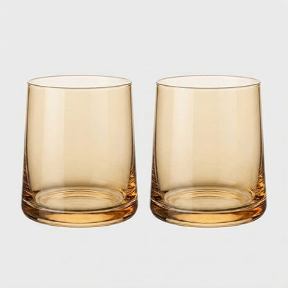 Set of two amber translucent drinking glasses side by side on a light gray background